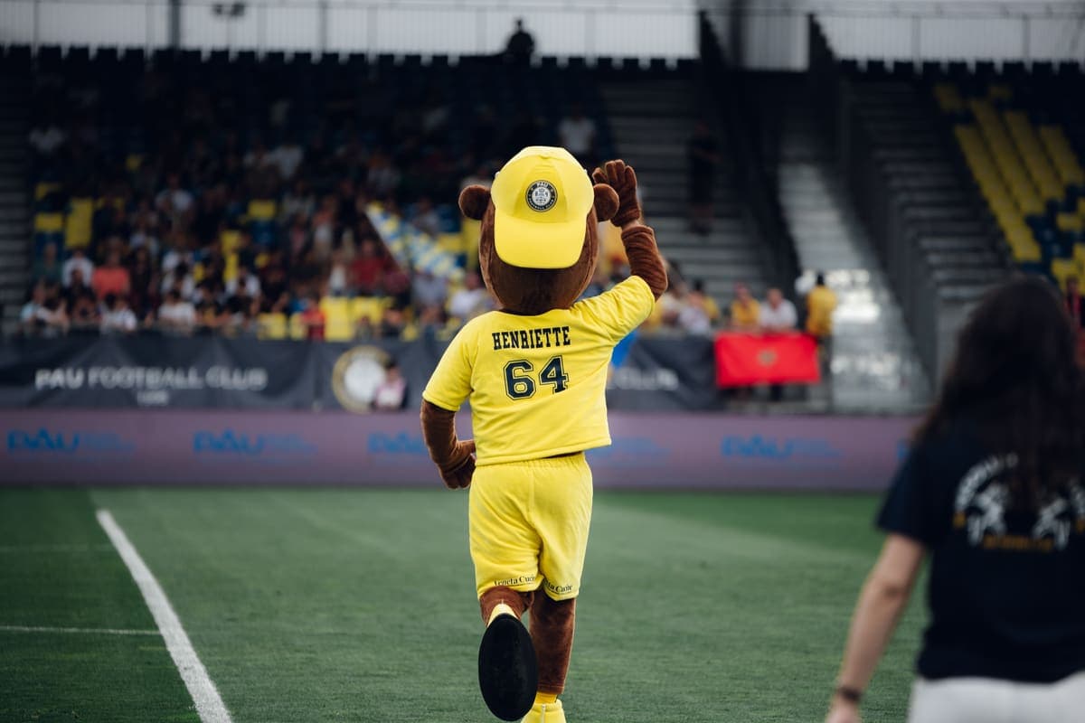 Henriette, la mascotte du Pau FC, salue les supporters au bord du terrain